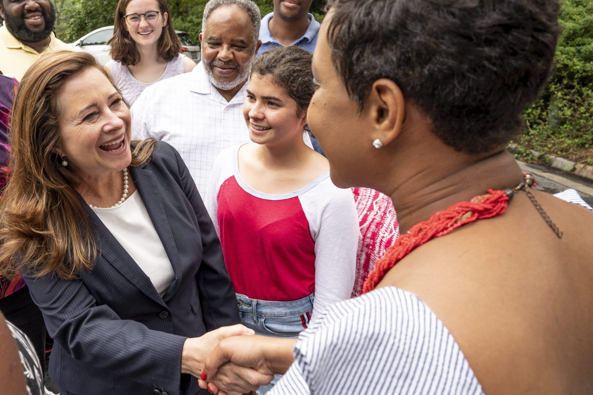Shelly shaking hands with a constituents, with other constituents gathered around Shelly